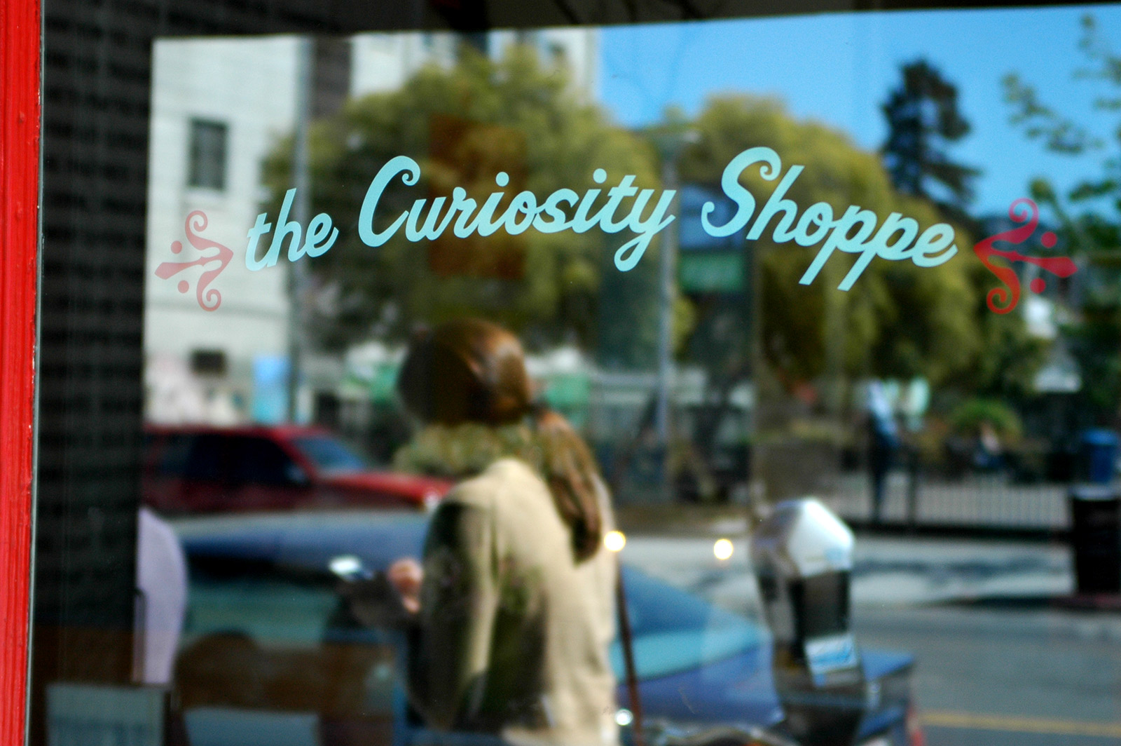 Photo show a woman walking by Curiosity Shoppe