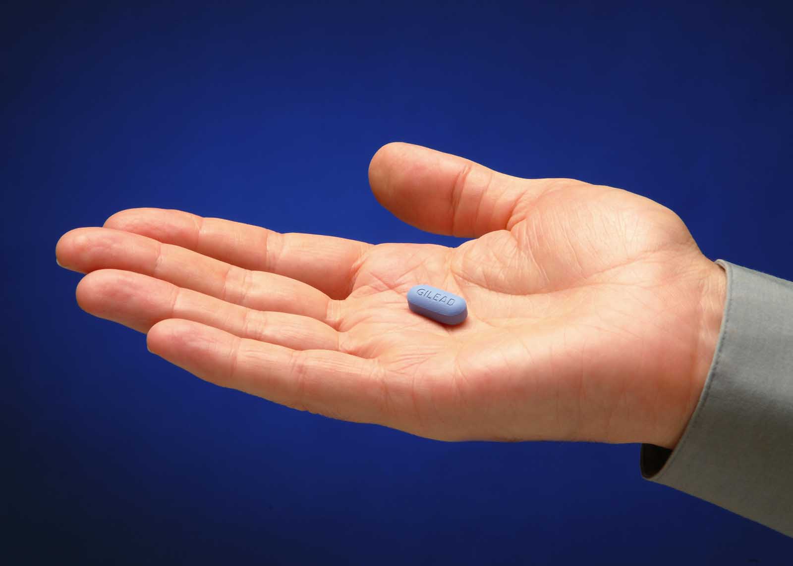 Photo courtesy of GIlead with a hand holding a small blue Truvada pill in the center of the palm.