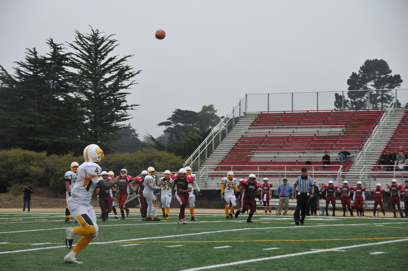 A football player runs to catch a ball.