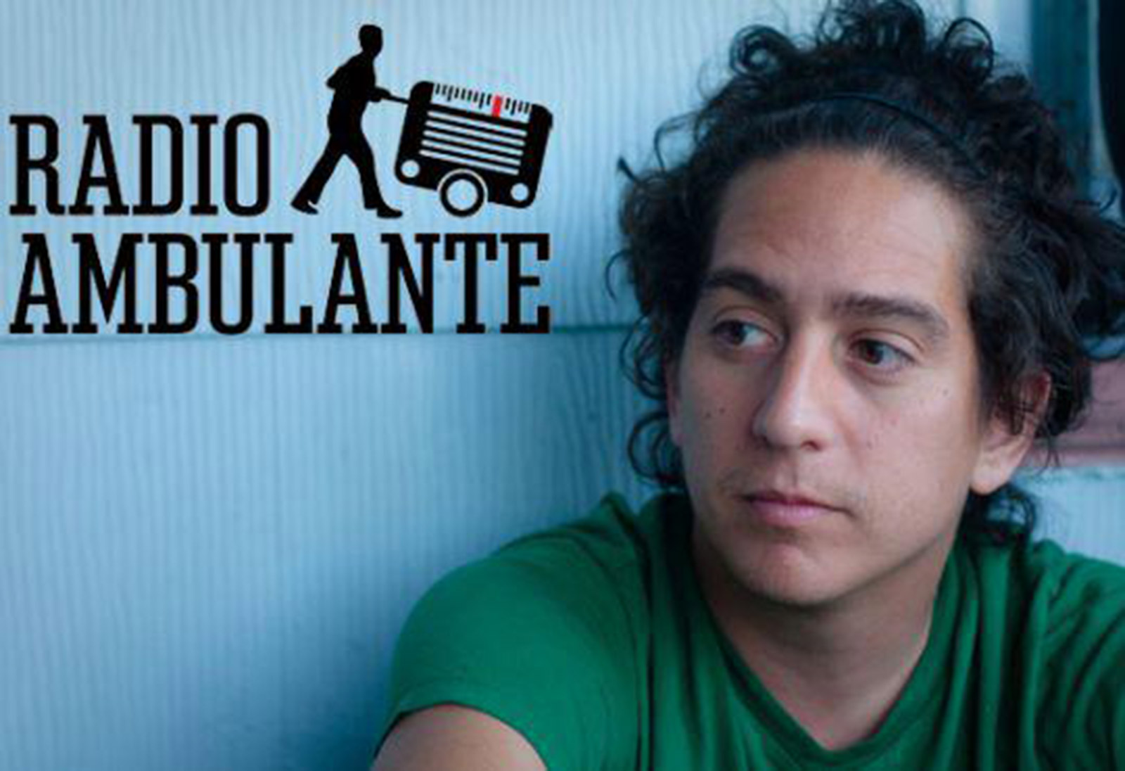 A photo of Daniel Alarcón, the executive producer of Radio Ambulante. Here he sits next to a blue wall, looking pensive.