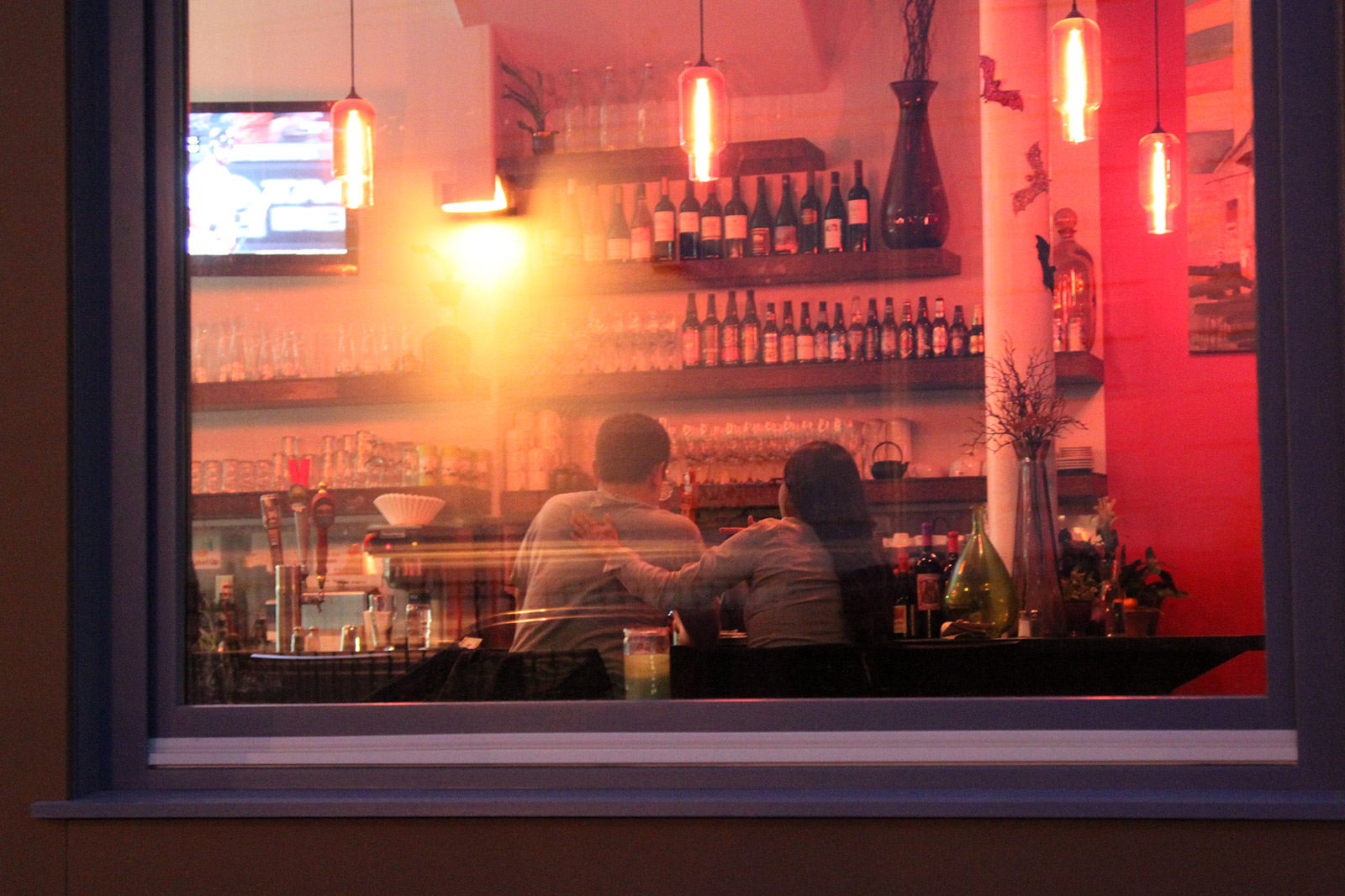 Image shows a woman rubbing a man's back in a bar.