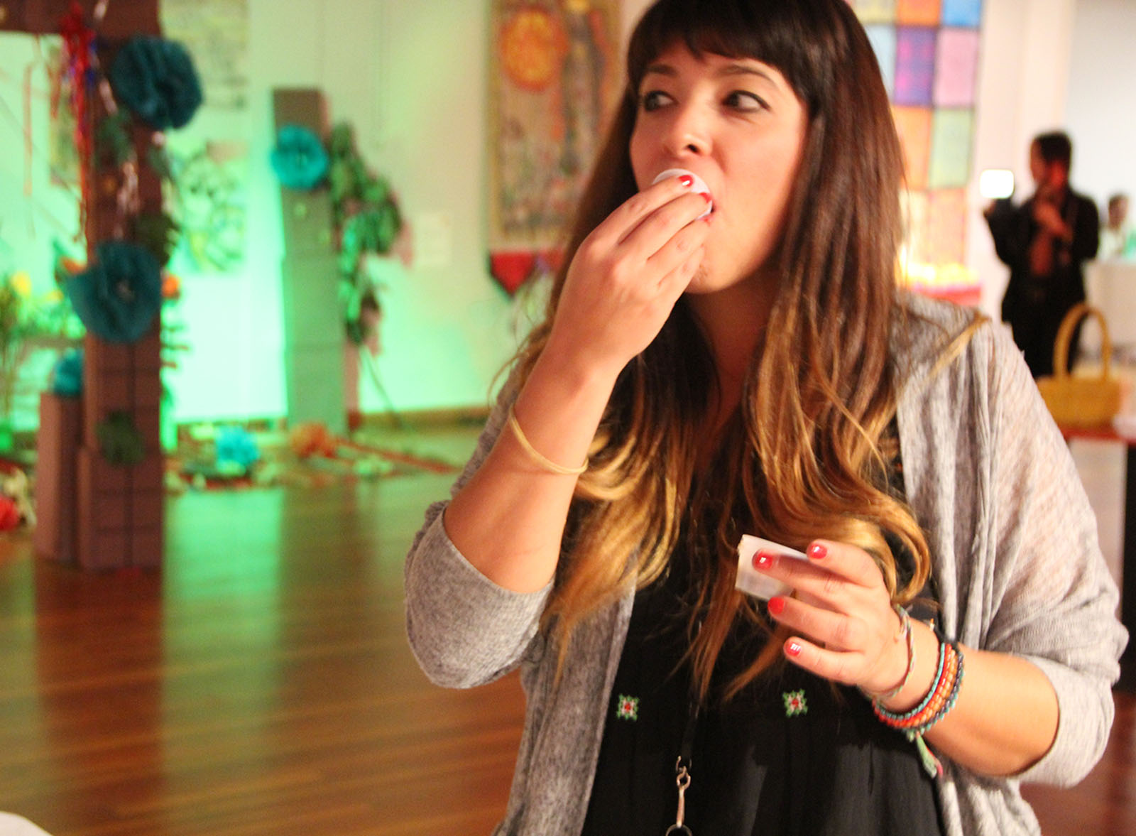 A woman happily eats a small cup of mole.