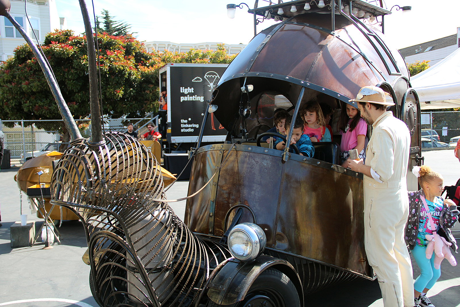 Kids play on a car shaped like a bug at On The Move: An Exploratorium Road Show at Buena Vista Horace Mann.