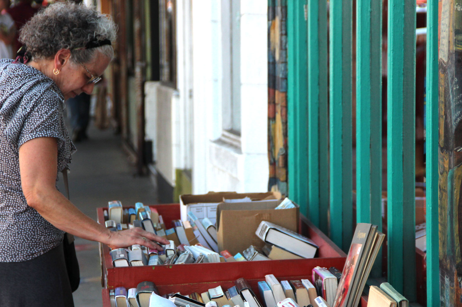 A woman looking at book titles outside of a bookstore.