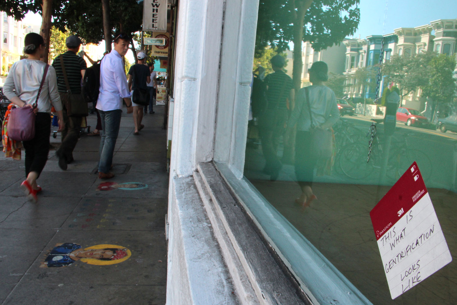 A sticker that says "This is what gentrification looks like" on a storefront window.