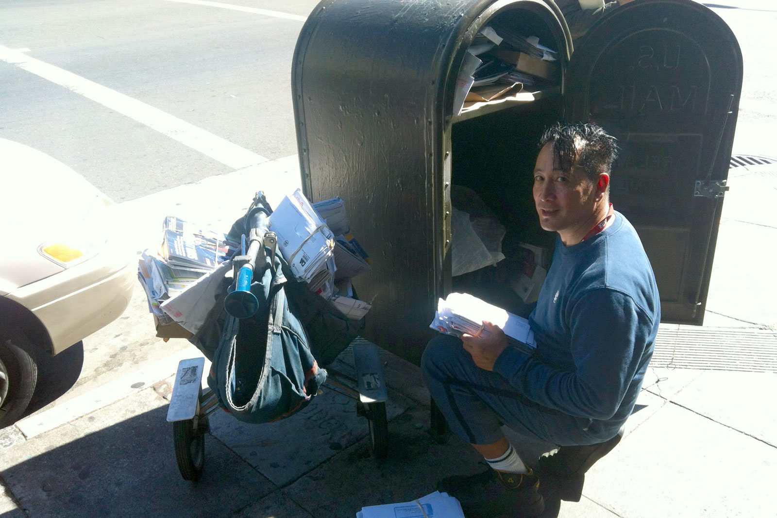 Mailman crouched next to a mailbox