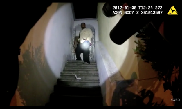 Gun points up staircase, toward a man in a spotlight standing in a doorway.
