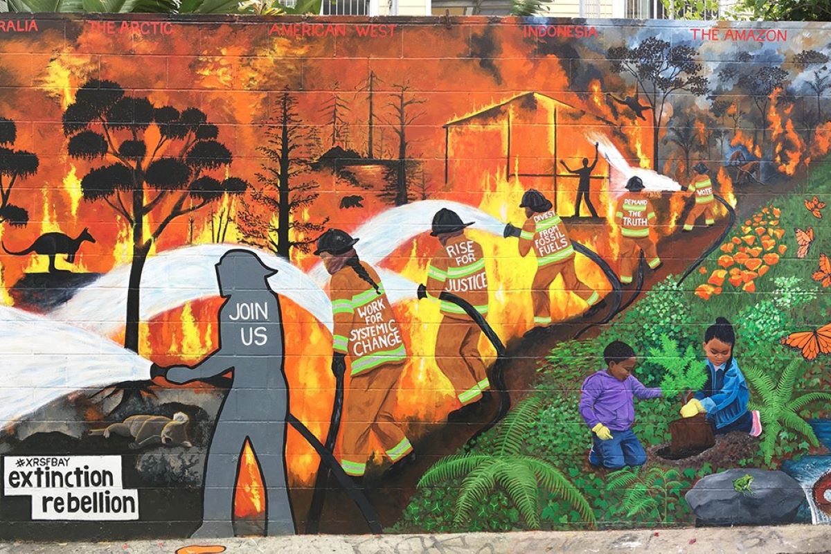 The new mural on clarion alley shows a line of firefighters holding a fire at bay from children playing in a lush forest landscape.