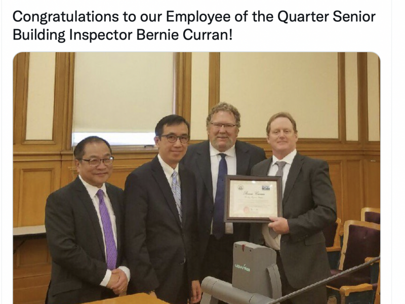A photo of four officials holding a commendation.