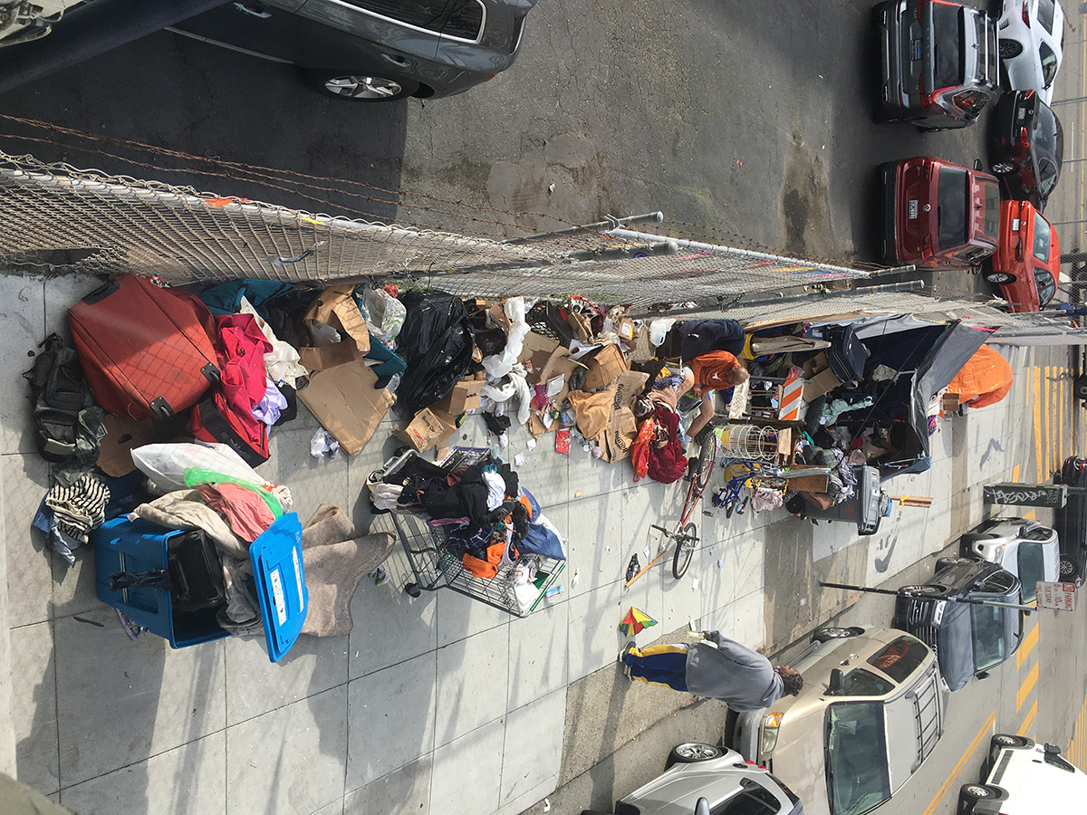 encampment with orange tent and additional structure fashioned from accumulated garbage and other items
