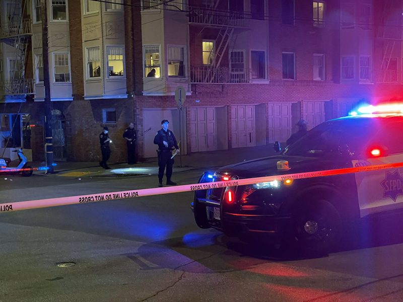 Police car with lights on behind caution tape.