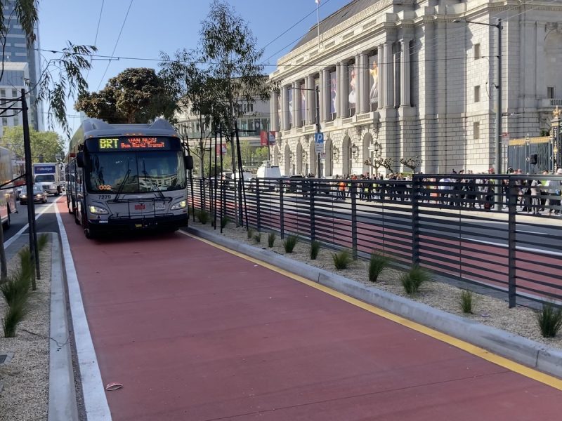A "BRT" bus pulls up on a painted red lane