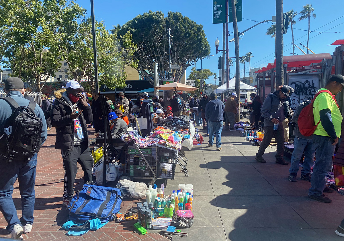 A group of people standing on a sidewalk.