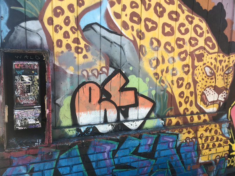 A phone booth next to a. mural of a spotted tiger.