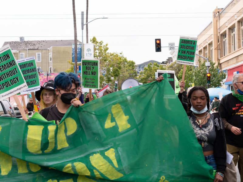 Abortion rights protesters hold up a sign that says “Stand Up 4 Abortion Rights”