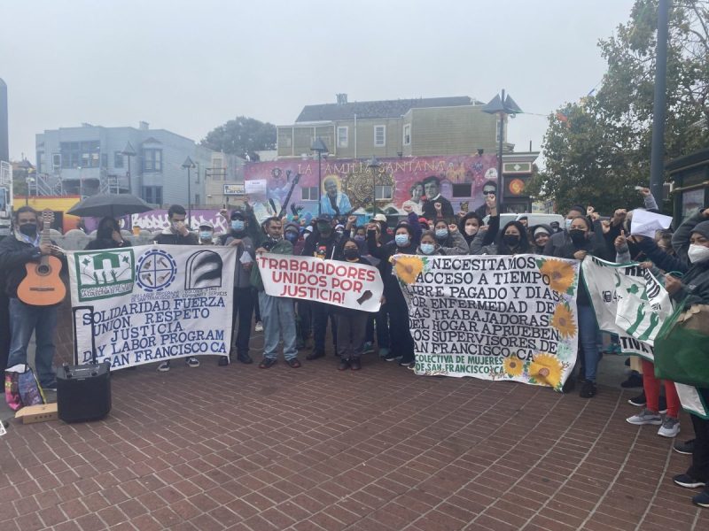 The Workers Rights Community Collaborative stand together with their fists up and holding signs that read, "Workers united for justice."