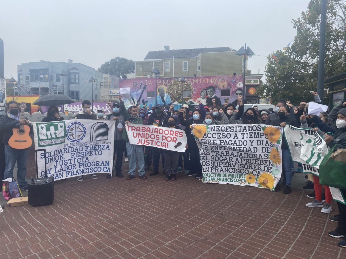 The Workers Rights Community Collaborative stand together with their fists up and holding signs that read, "Workers united for justice."