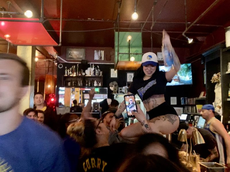 A woman pours tequila into bargoers' mouths.