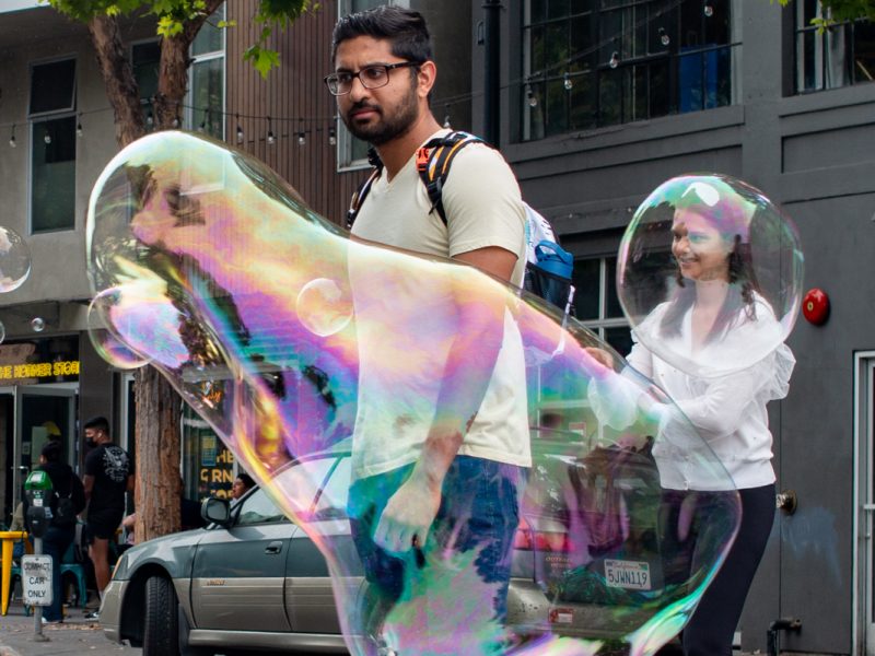 two people playing with air bubbles on Valencia Street