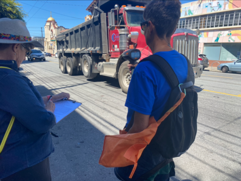 a women on the right holds a speed gun while the women on the left records the speeds