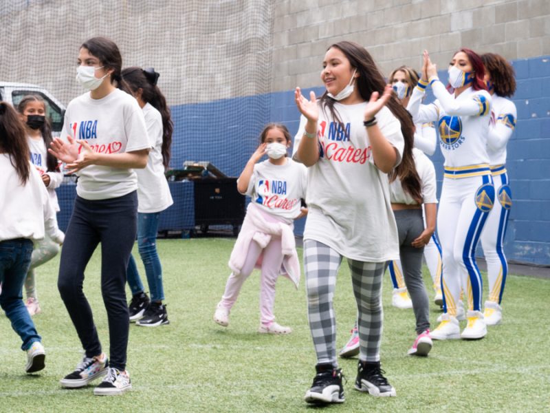 A group of girls from the Boys and Girls Club dance with Warriors cheerleaders