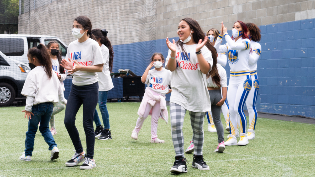 A group of girls from the Boys and Girls Club dance with Warriors cheerleaders