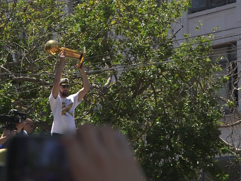 Klay Thompson holds a trophy in the air.