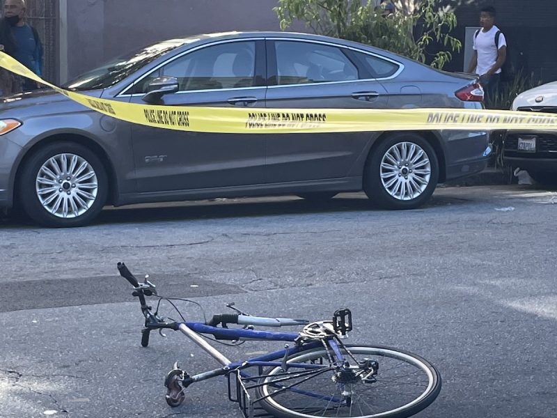 A bicycle on the ground, under police tape, missing its front wheel