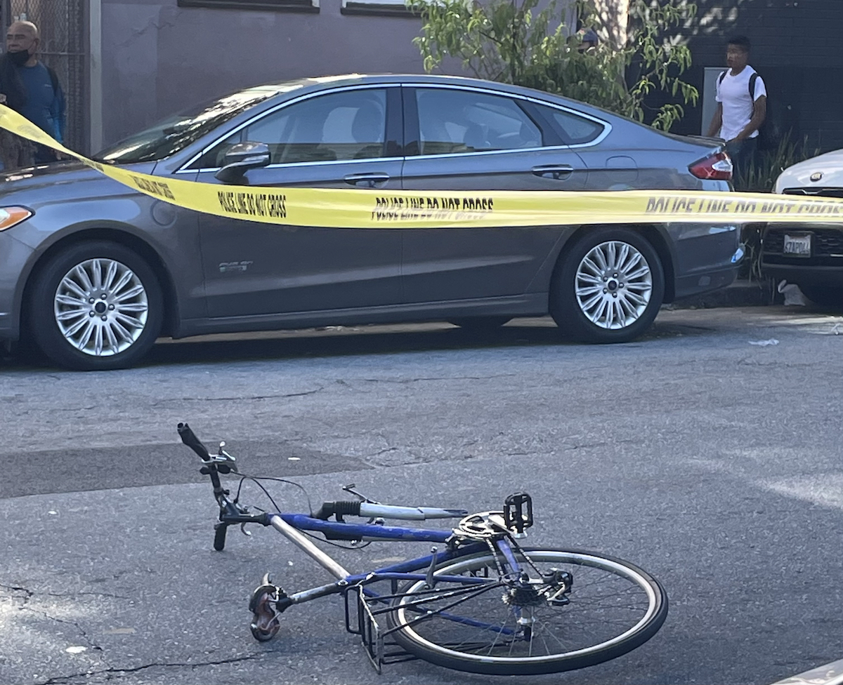 A bicycle on the ground, under police tape, missing its front wheel