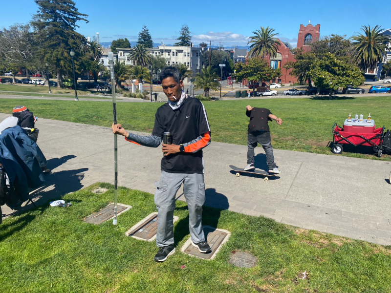 a man holds a flow stick in his right hand, a beer in his left hand, and a cigarette between his teeth