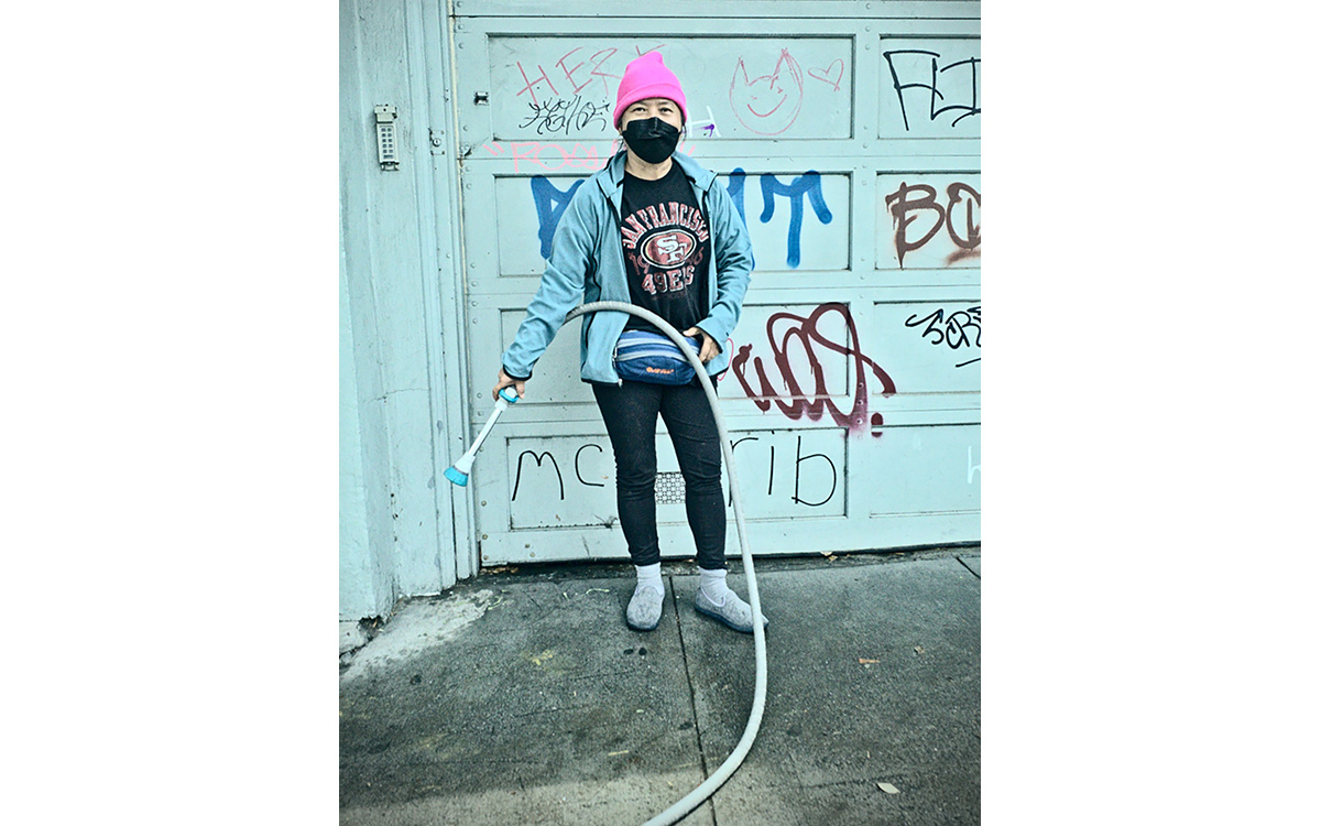 A woman with a pink hat cleaning up with a hose.