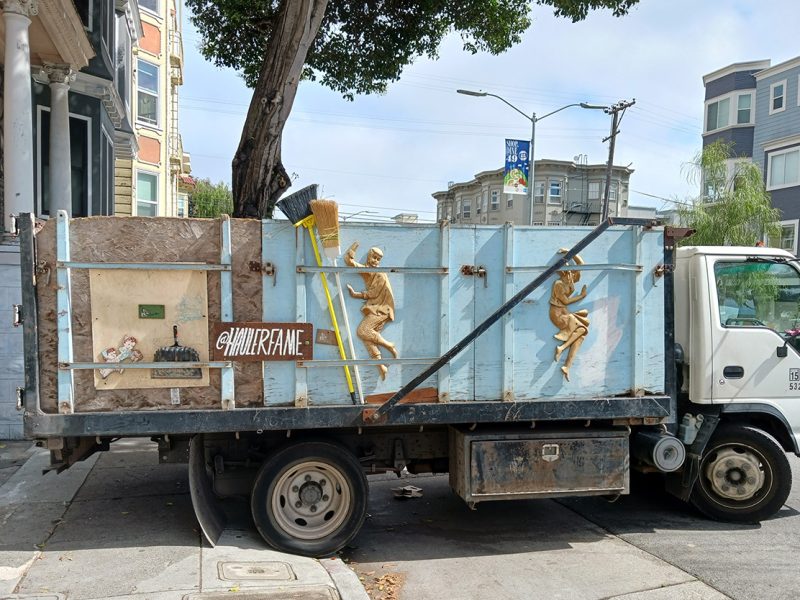 A open hauling truck with art on the side.