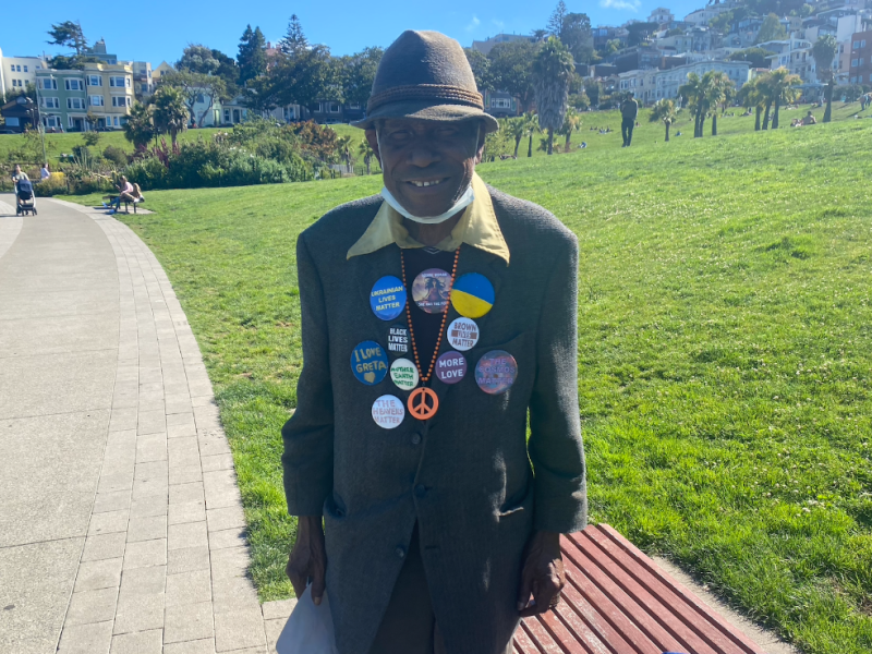 Horace Thomas in his suit, buttons and orange peace necklace.