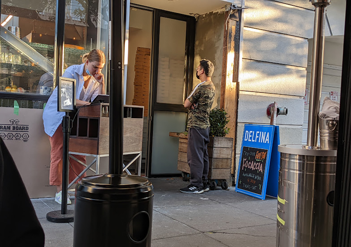 Outside of Delfina with a man standing at the door and a woman inside.