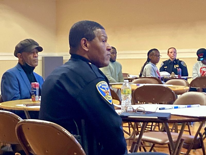 a police chief sitting at a pubic meeting.