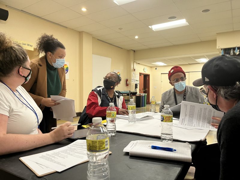 People in discussion at a table with papers and water bottles