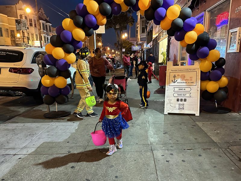 A young girl passing through a balloon arbor