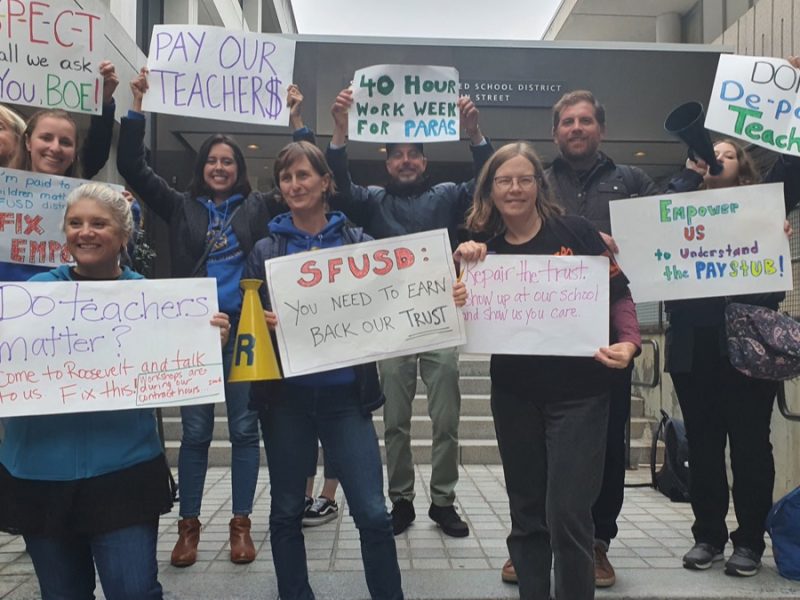 Teachers carrying signs outside 555 Franklin St. in protest of San Francisco Unified School District's ongoing payroll fiasco