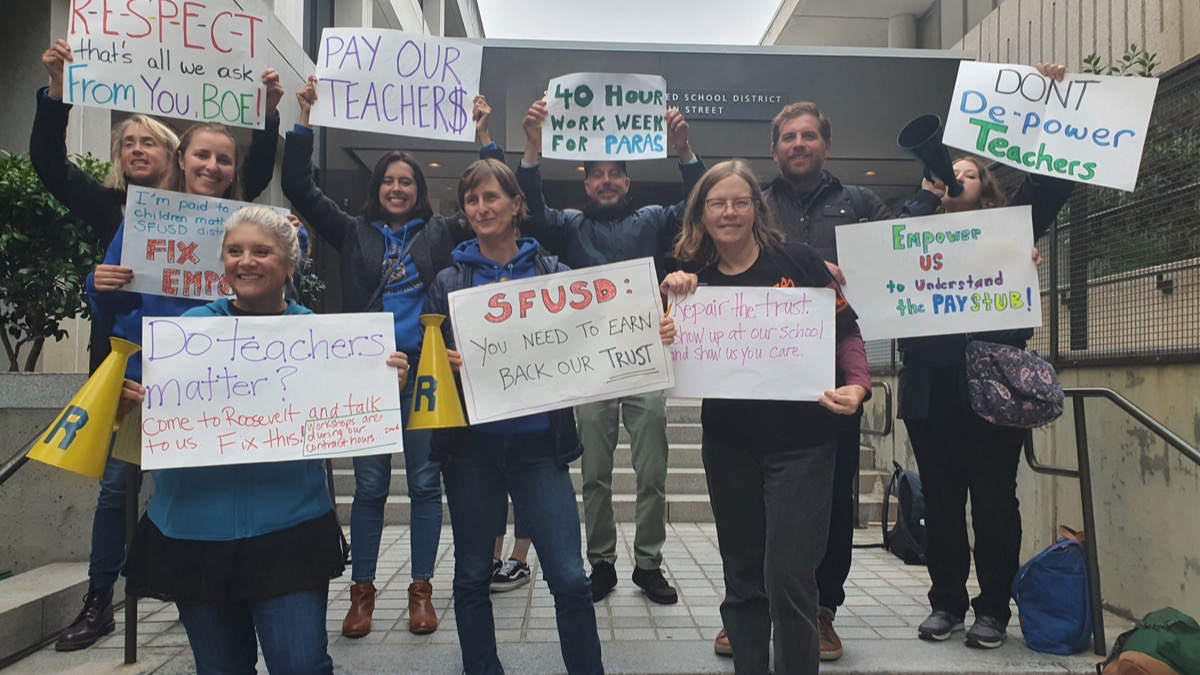 Teachers carrying signs outside 555 Franklin St. in protest of San Francisco Unified School District's ongoing payroll fiasco