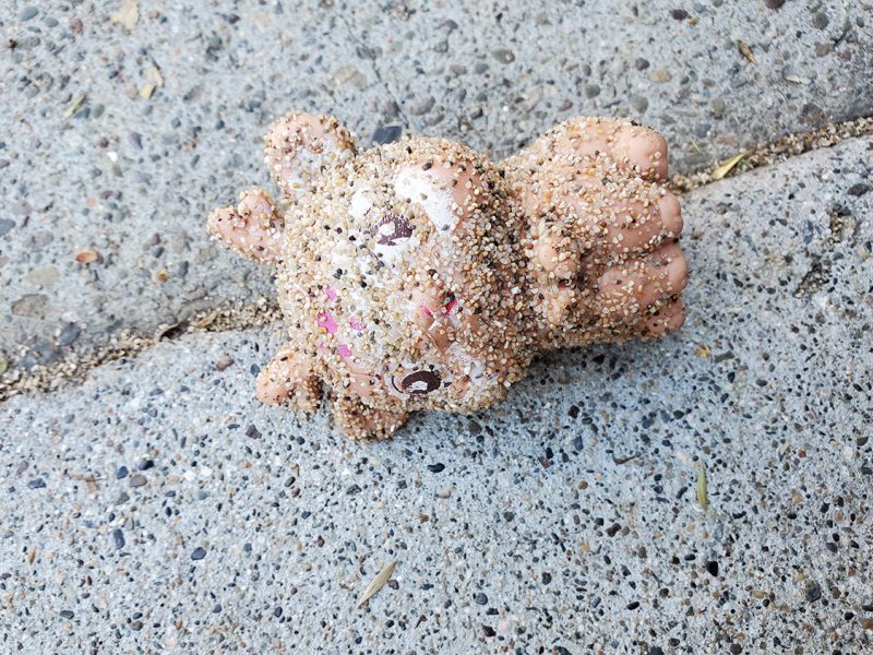 A toy doll on the sidewalk.