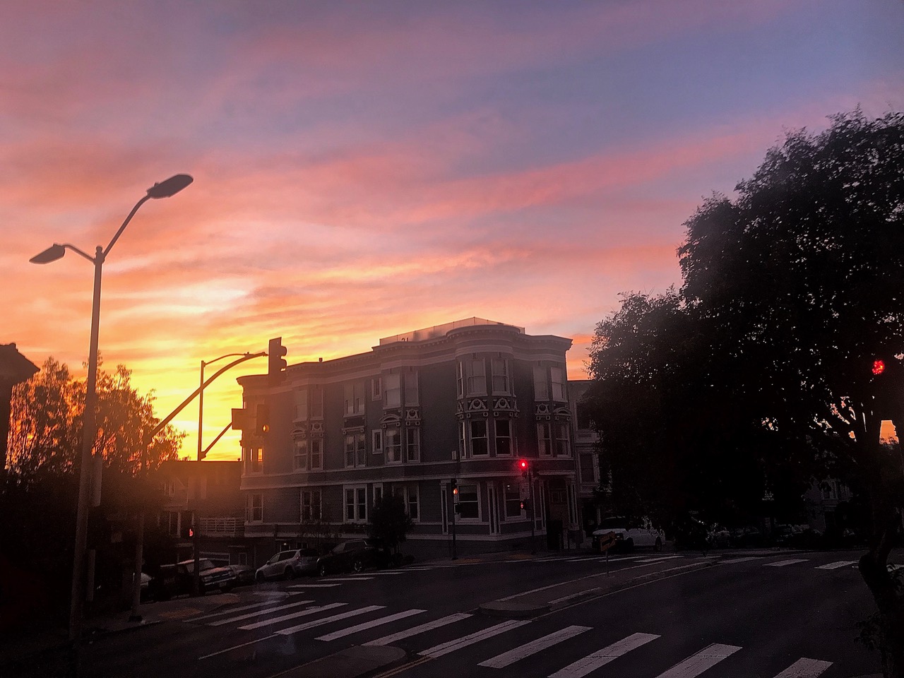 Sunrise, purple sky, lampposts and houses.