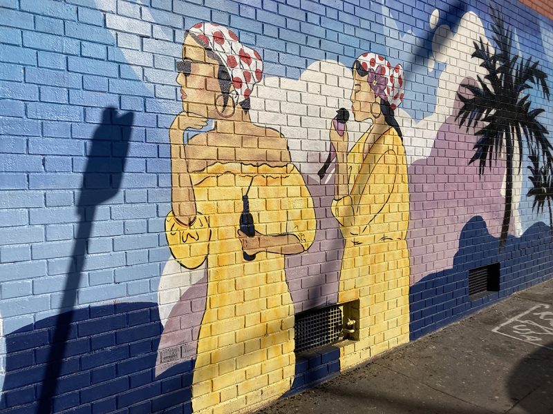 A mural of two women with yellow dresses and polka dot head gear