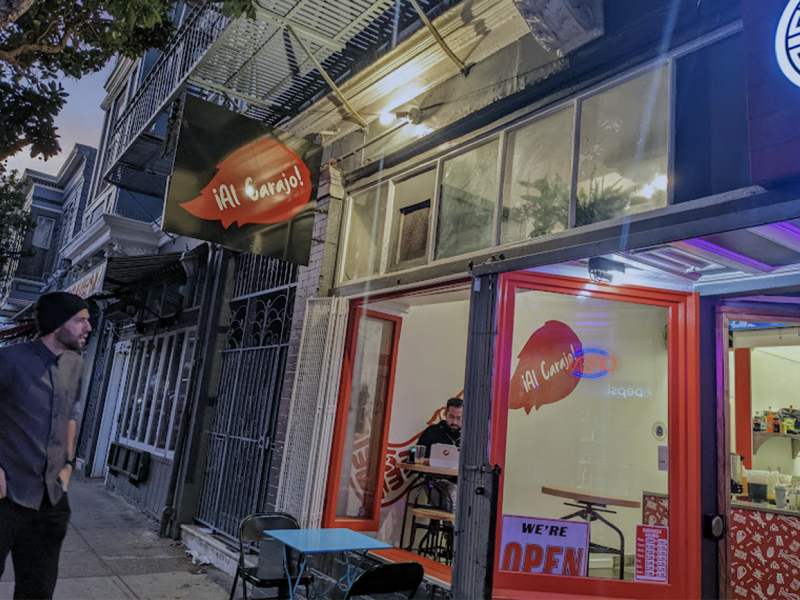 The outside of a taqueria with a man looking in the restaurant.