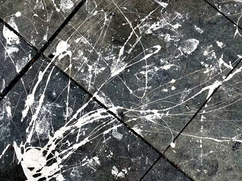 White paint splattered on the sidewalk .
