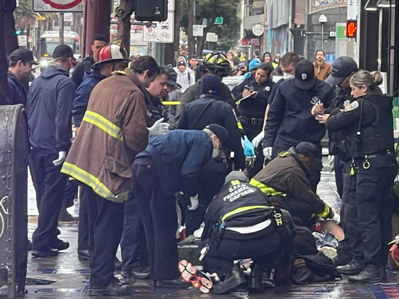 Paramedics render aid to two men who suffered gunshot wounds in front of the shop Smoker Friendly near the 16th Street BART Station on Tuesday, Dec. 27, 2022.