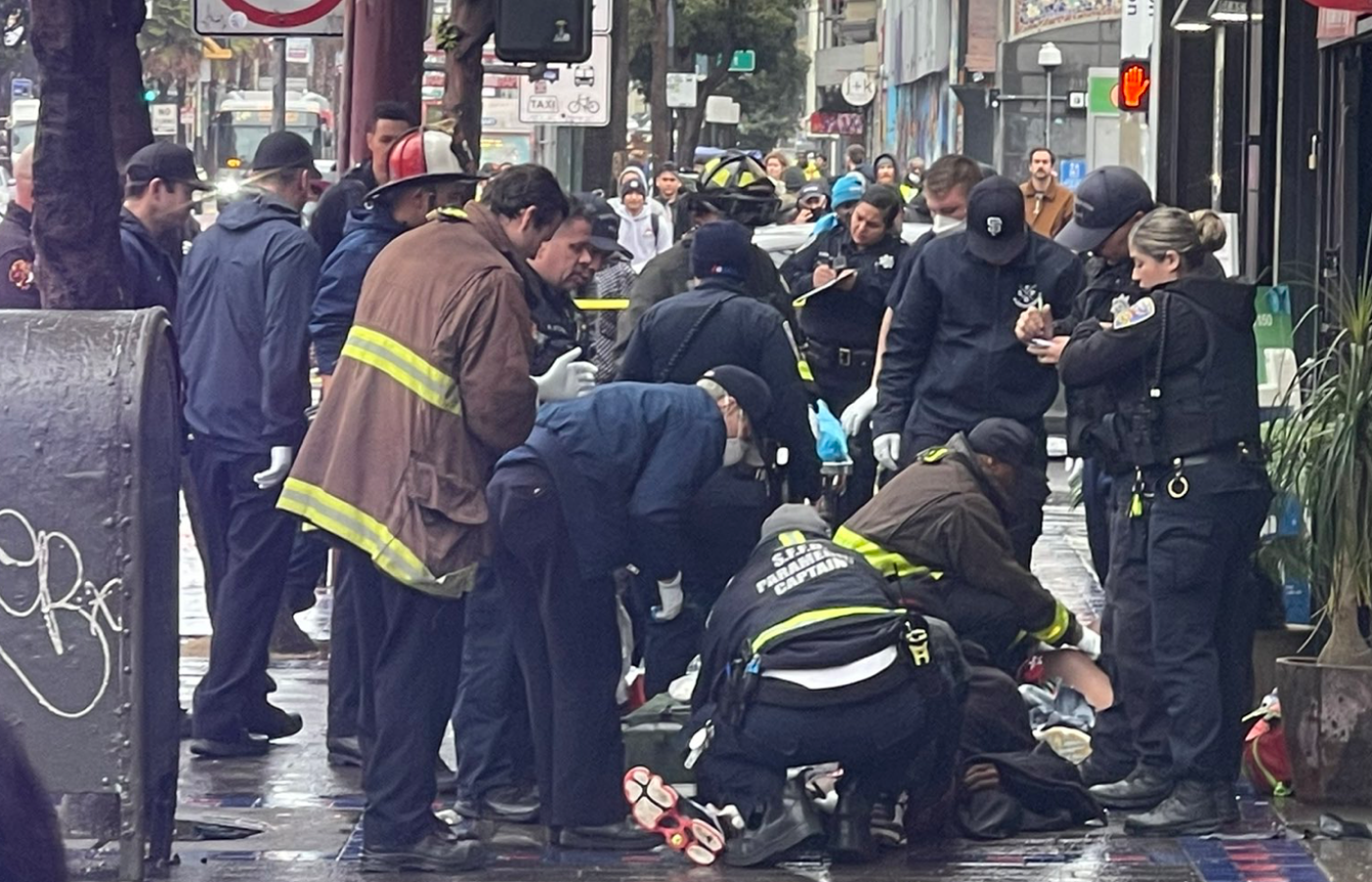 Paramedics render aid to two men who suffered gunshot wounds in front of the shop Smoker Friendly near the 16th Street BART Station on Tuesday, Dec. 27, 2022.