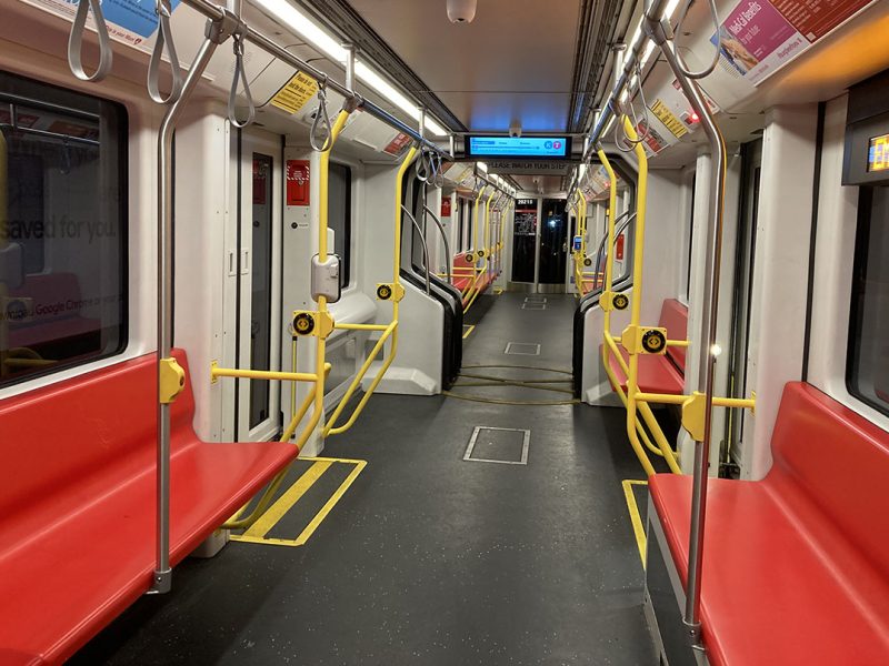 The interior of a muni light rail, red seats and empty.