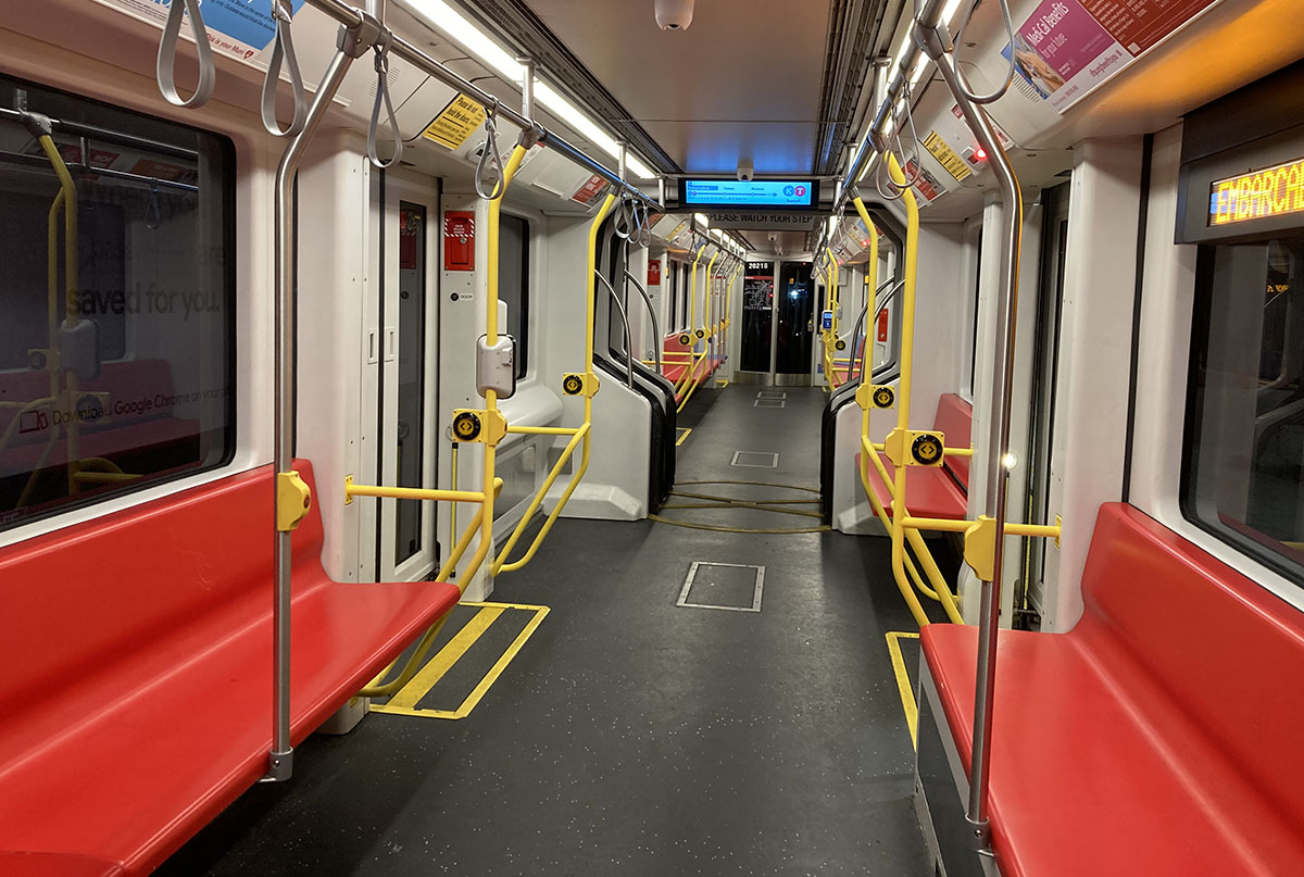 The interior of a muni light rail, red seats and empty.