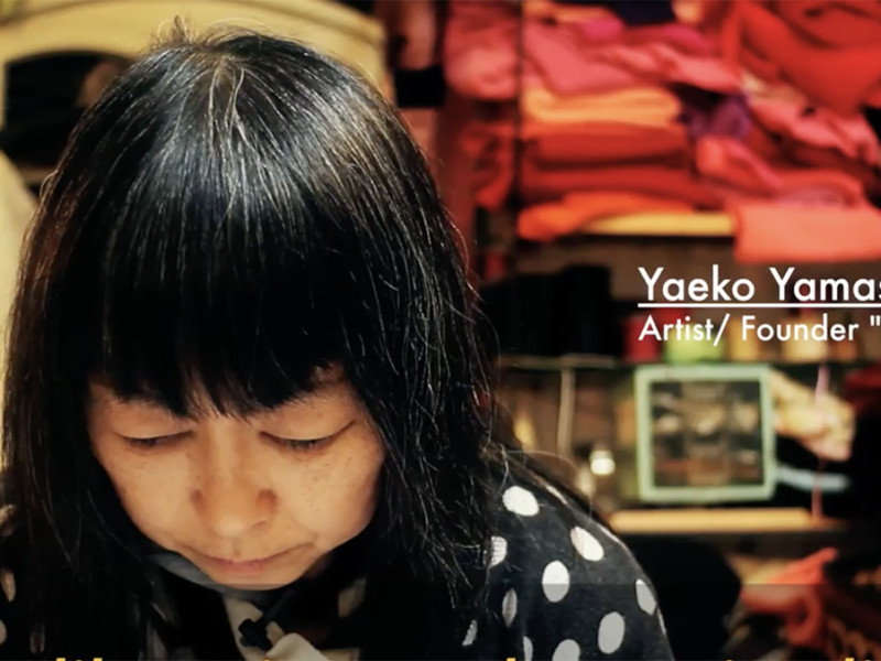 A woman, head slightly down as she works behind the counter of a store