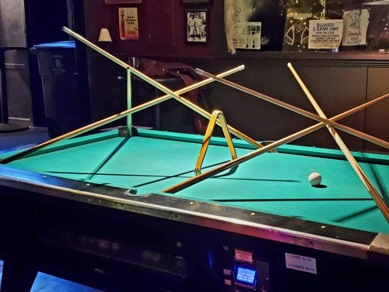 A green felt topped pool table with a stick structure on top of it.